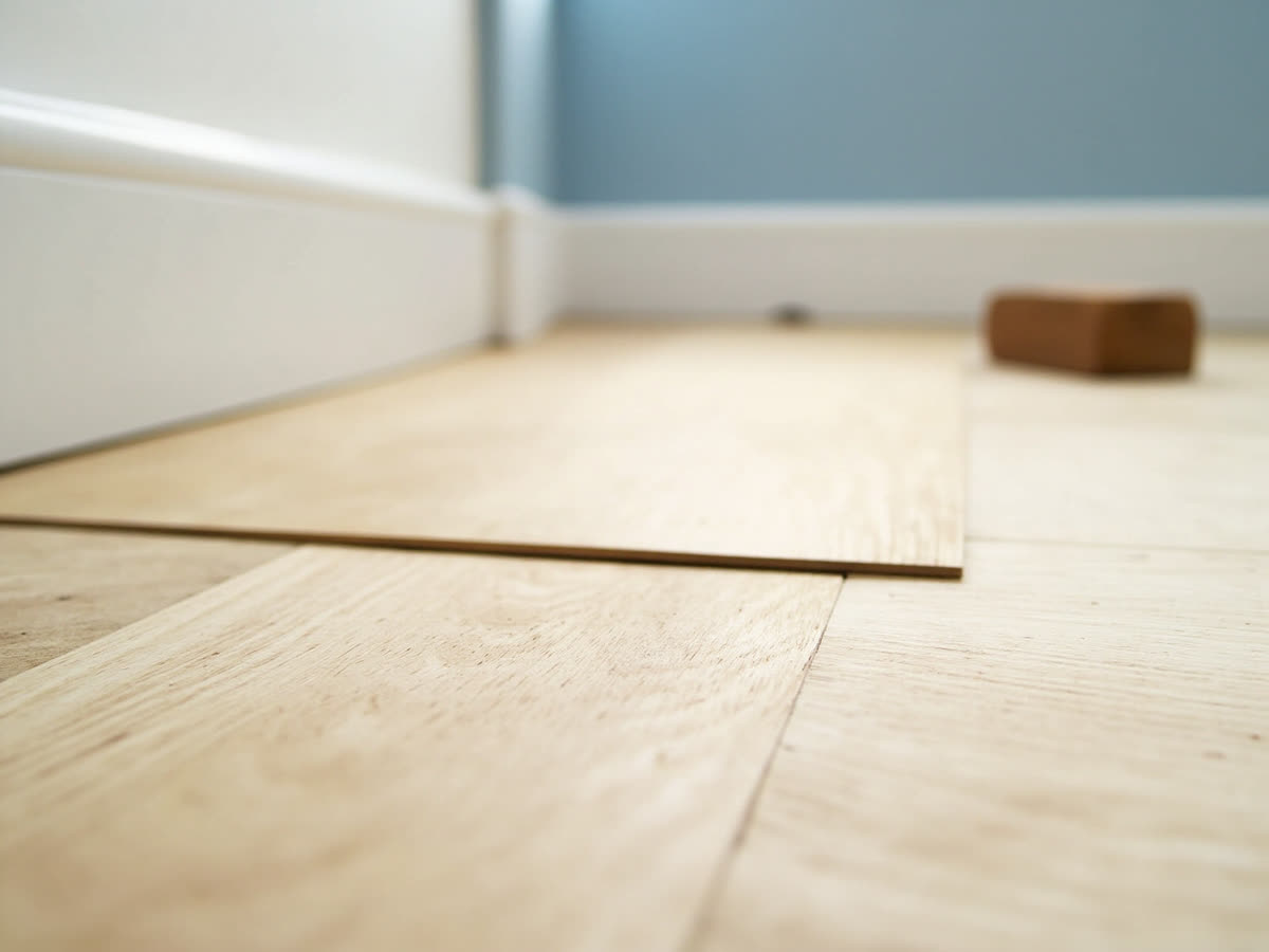 Bodenverlegung: neu verlegtes Laminat in heller Eiche mit weißen Sockelleisten